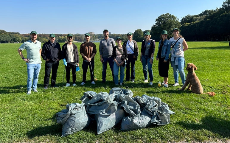 Das Team RE:CIRCLE nach dem Cleanup im Hamburger Stadtpark mit gesammelten Müllsäcken und einem Hund auf der Wiese.